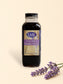 Bottle of LML Lavender Simple Syrup on a marble surface with a beige background