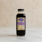 Bottle of LML Lavender Simple Syrup on a marble surface with a beige background