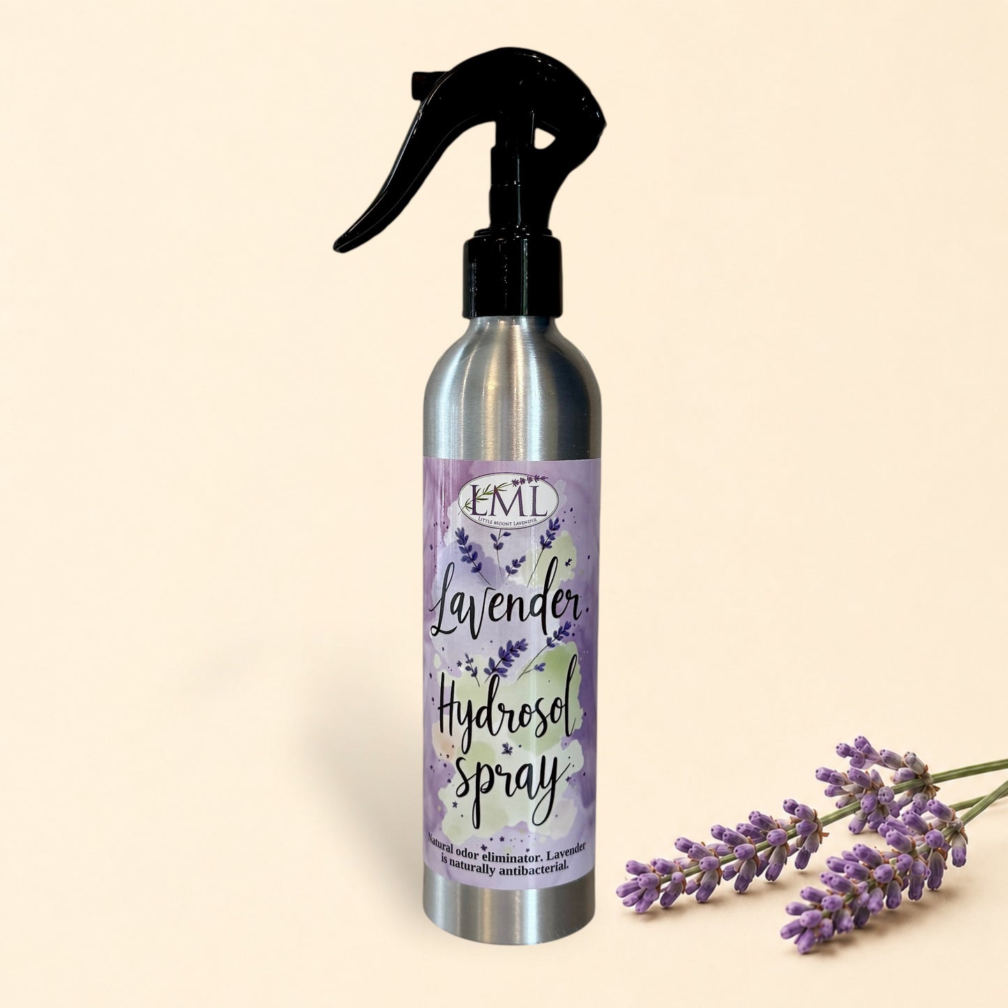 Silver spray bottle with lavender hydrosel label on a tiled wall background