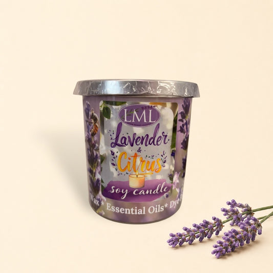 Little Mount Lavender soy candle in a purple glass jar surrounded by fresh oranges and essential oil on a table.