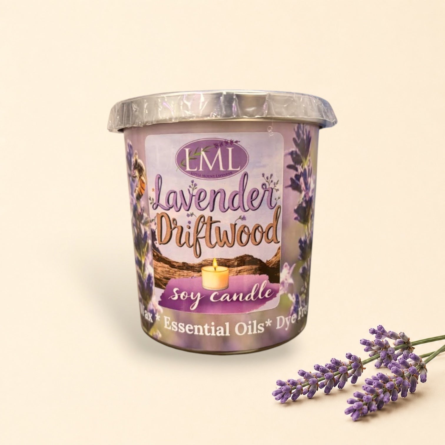 Little Mount Lavender driftwood and lavender soy candle in a glass jar, set on a beach at sunset.