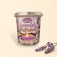 Little Mount Lavender driftwood and lavender soy candle in a glass jar, set on a beach at sunset.