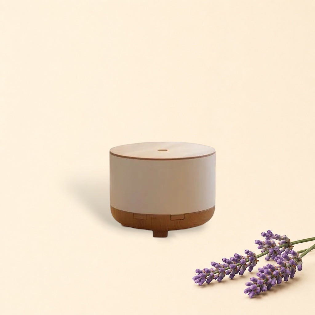 Little Mount Lavender Drum Mist ultrasonic diffuser with wood grain base and white top on a desk with a plant and book.