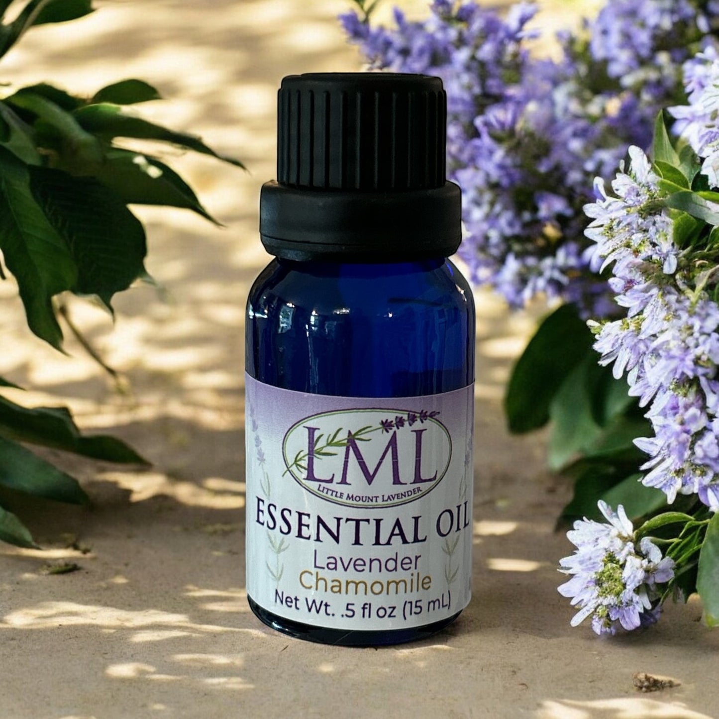 Little Mount Lavender essential oil bottle in blue glass, featuring a lavender and chamomile label, set in nature.
