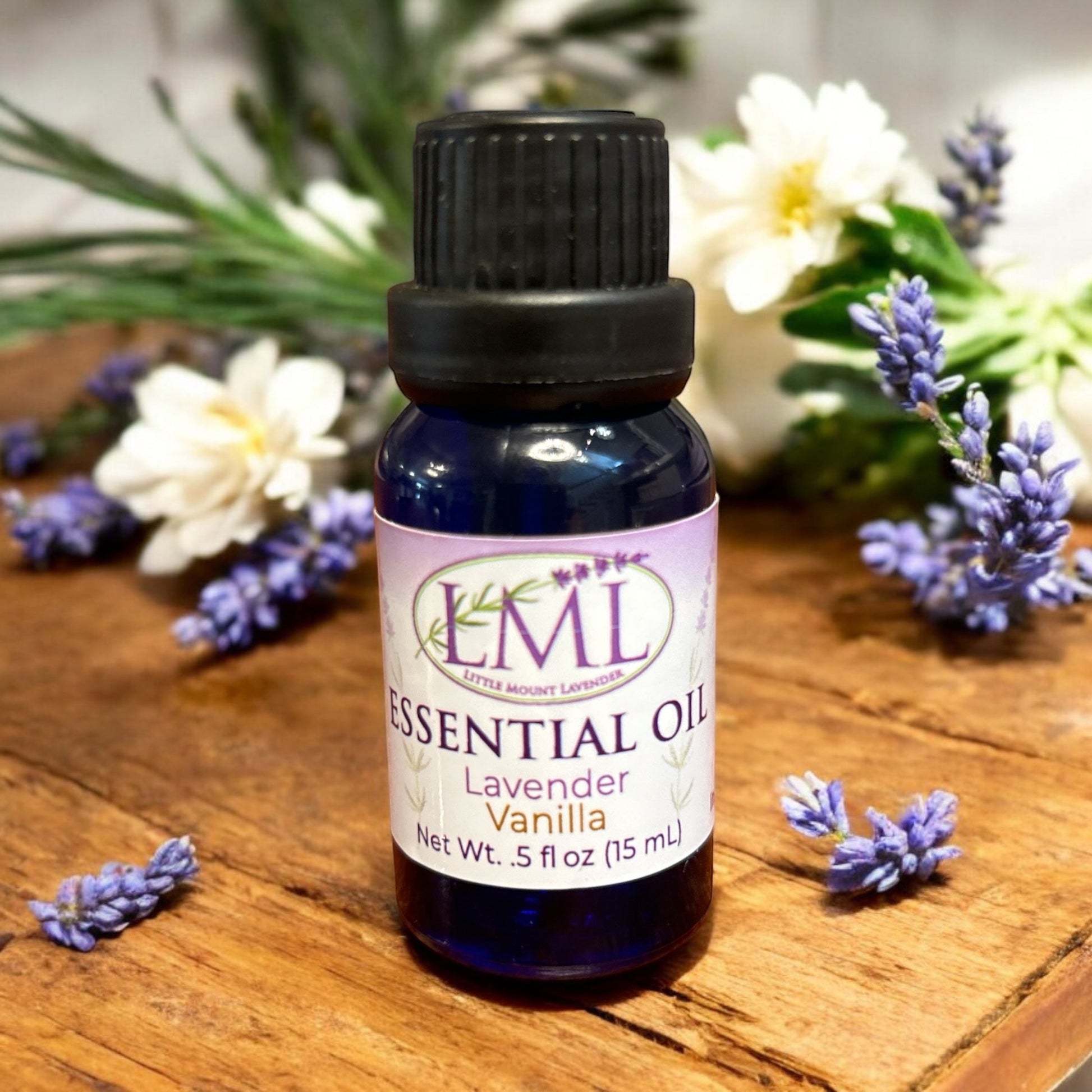 Little Mount Lavender essential oil bottle in lavender and vanilla scent, set on a wooden table with fresh flowers.