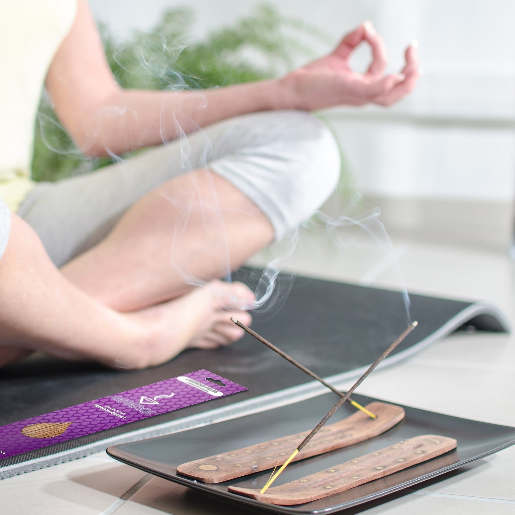 Little Mount Lavender incense sticks burning on wooden holders with a person meditating in the background.
