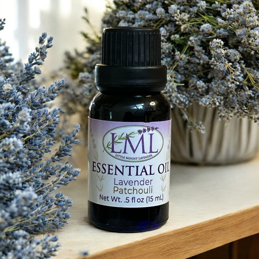 Little Mount Lavender essential oil bottle with lavender and patchouli blend, set against dried lavender flowers.