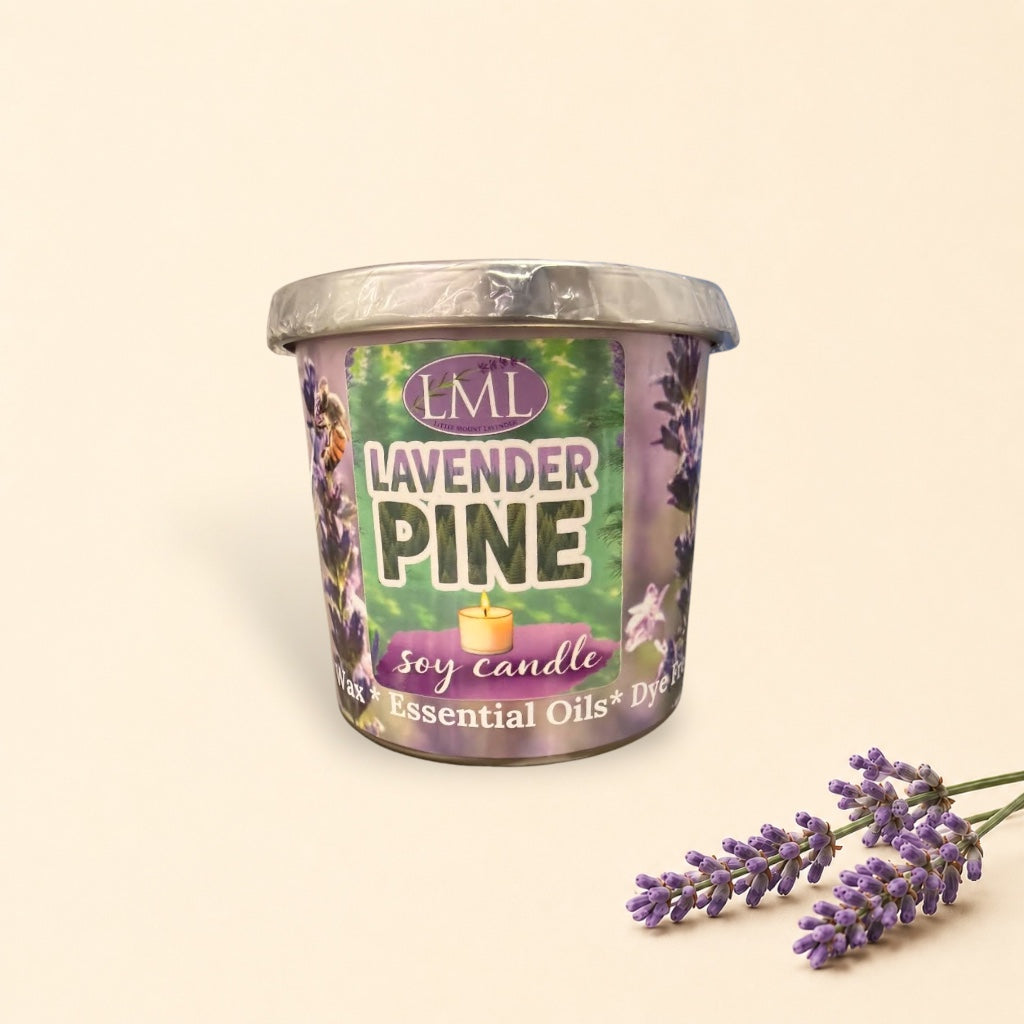 Little Mount Lavender soy candle in a floral glass jar on a wooden ledge with a blurred forest mountain background.