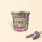 Little Mount Lavender soy candle in a floral glass jar on a wooden ledge with a blurred forest mountain background.