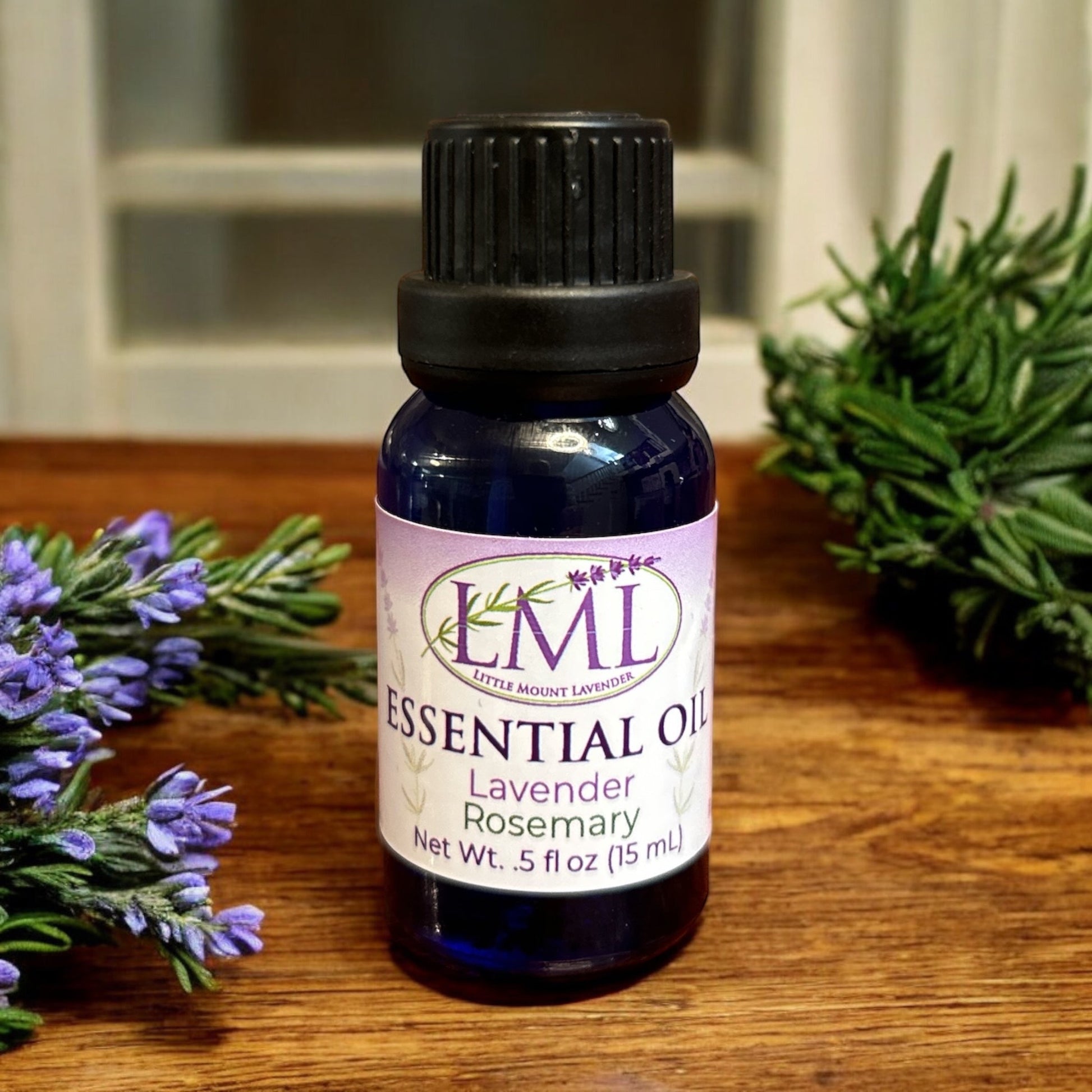 Little Mount Lavender essential oil blend with lavender and rosemary in a blue glass bottle on a wooden surface.