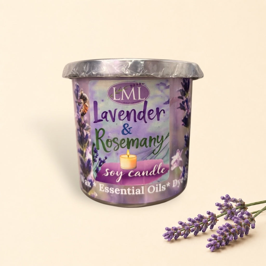 Little Mount Lavender soy candle in a purple glass jar with rosemary and lavender sprigs on a rustic wooden table.