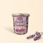 Little Mount Lavender soy candle in a decorative glass jar with lavender floral print on a rustic wooden table.