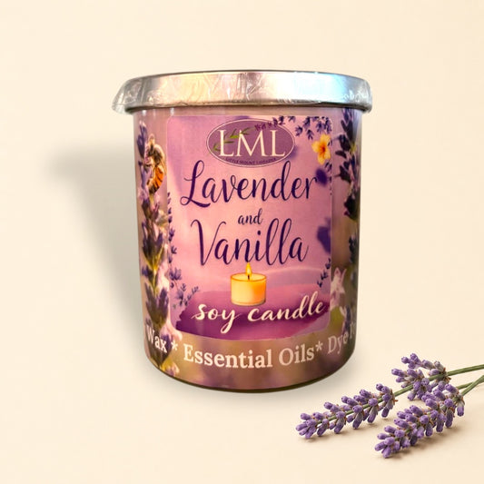 Little Mount Lavender soy candle in a purple glass jar with lavender print, set on a wooden table with white flowers.
