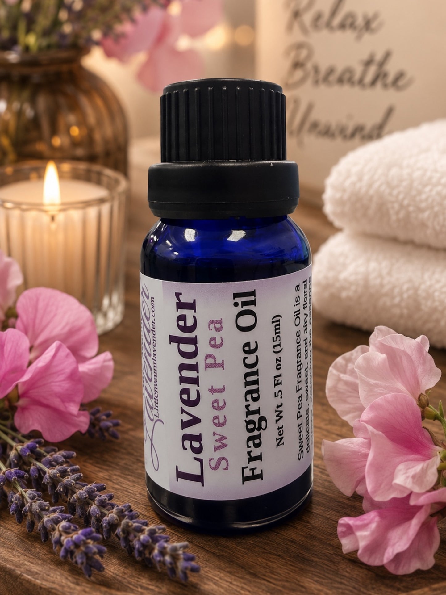 Little Mount Lavender Sweet Pea fragrance oil in a cobalt blue glass bottle with fresh lavender sprigs on a beige background
